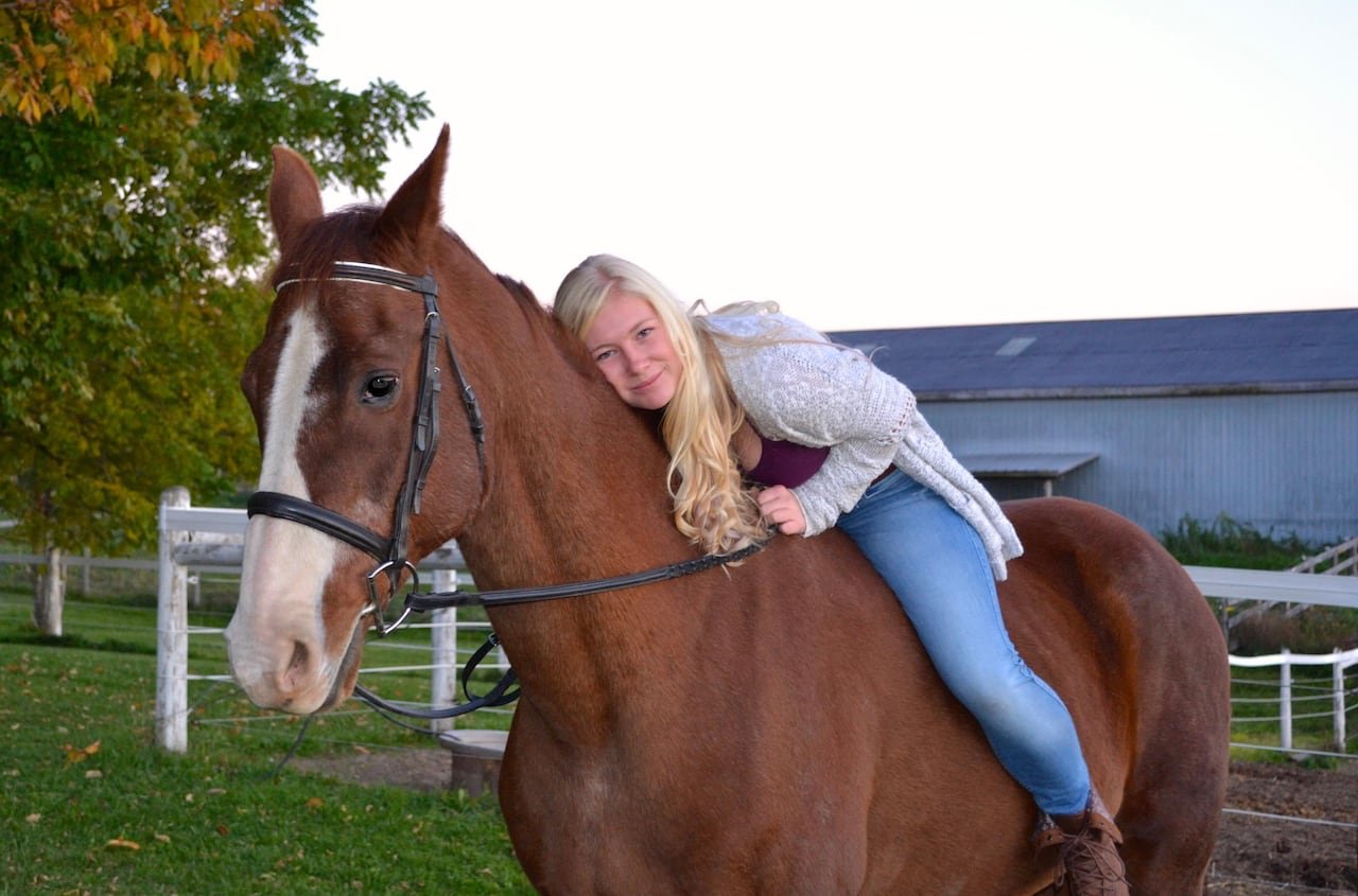 default-100 A woman sitting bareback on a horse bends down to hug it.