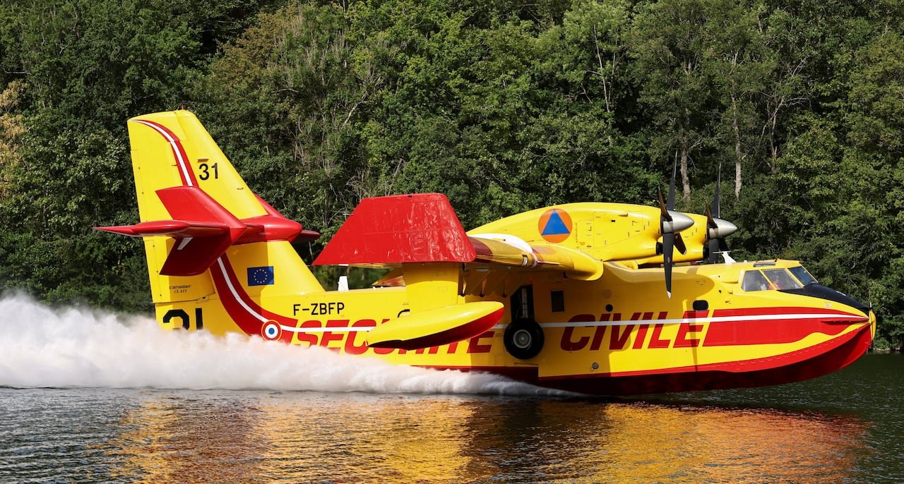 A Canadair aircraft scoops up water while flying over the river.
