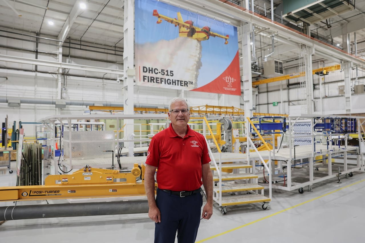 A man in a red polo stands in a factory.